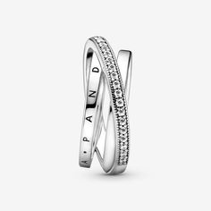 Layer up with the Crossover Pavé Triple Band Ring. This sterling silver ring features three bands, with one diagonally overlapping the other two. One inner band has the Pandora logo, the other inner band is polished and the outer band features clear cubic zirconia pavé stones framed by micro-beading. All three bands merge at the back of the ring band. Inspired by the spiral structure of the solar system, this ring brings a sleek, structural sophistication to any look. Available in-store and onli Cute Dainty Jewelry, Pandora Logo, Triple Band Ring, Pandora Ring, 7 Ring, Pave Band, Pandora Rings, Halo Earrings Studs, Pave Ring