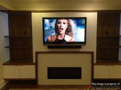 a flat screen tv mounted to the side of a wall next to a fire place