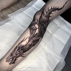 a man's arm with a dragon tattoo on it, sitting on a bed