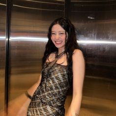 a pregnant woman posing in front of a shiny metal wall with her hands on her hips