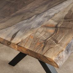 a wooden table sitting on top of a cement floor next to a metal leg vase