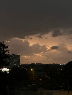 the sky is very dark and cloudy at night, with buildings in the foreground