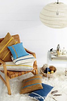 a chair and some pillows on a white rug in a room with a lamp hanging above it