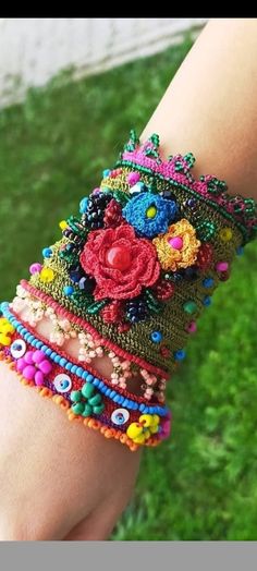 a woman's arm with colorful beaded bracelets and flowers on the wrist