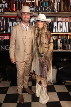 a man and woman standing next to each other in front of a shelf full of hats