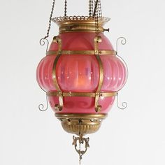 a pink and gold hanging light fixture with chain around it's neck, on a white background