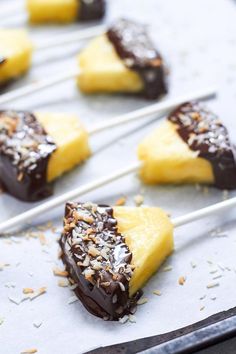 chocolate dipped pineapples are sitting on a baking sheet with toothpicks in them