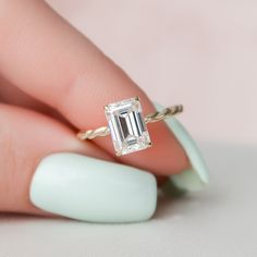 a woman's hand holding a ring with an emerald stone