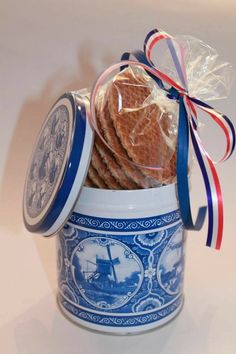 cookies in a blue and white container with ribbon around the top, wrapped in cellophane