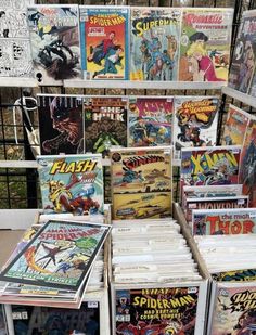 many comics are stacked on top of each other in front of a metal fence with black iron bars