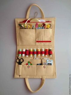 a tote bag hanging on the wall with sewing supplies in it and some scissors