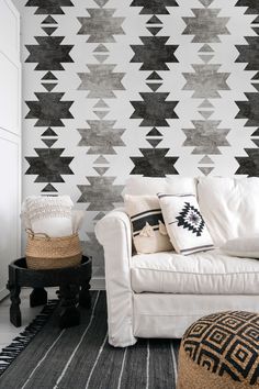 a white couch sitting in front of a wall with black and white designs on it