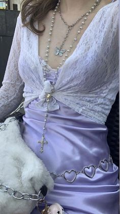 a woman in a purple dress holding a white teddy bear and wearing a chain around her waist