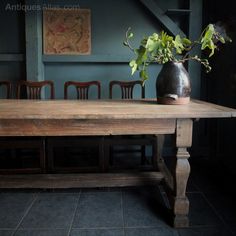 a wooden table with chairs and a vase on it