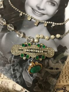 Does a handcrafted antique Assemblage necklace. I started with an antique brooch which I purchased from an antique store. The tag said it was from the 1920s. It is green and Clear rhinestones. It may have a few missing rhinestones but this does add to the charm of the piece since it is an antique. I added a green marbled colored charm to the bottom. One side of the chain is clear rhinestone rosary style beads.  The opposite side combines pho pearls and chain. I added a vintage rhinestone necklac Vintage Green Jeweled Necklaces, Vintage Green Jeweled Necklace, Vintage Green Jeweled Jewelry, Vintage Jeweled Necklace For Vintage Events, Vintage Green Necklace With Vintage Charm, Vintage Green Necklaces With Vintage Charm, Green Vintage Necklaces With Vintage Charm, Vintage Green Jewelry For Vintage Events, Green Vintage Jewelry For Vintage Events