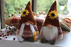 two stuffed gnomes sitting on top of a window sill next to each other