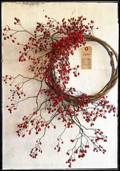 a bunch of red berries hanging from a branch on a white wall with a price tag