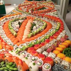 sushi rolls arranged in the shape of a heart on a table with peppers and carrots