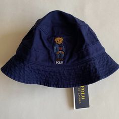 100% Authentic Mens Polo Ralph Lauren Polo Bear Twill Bucket Hat (Msrp $69.50). This Hat Is Brand New With Tags! Polo Ralph Lauren's Twill Bucket Hat Features The Iconic Polo Bear Dressed In A Denim Jacket, Cable-Knit Sweater And Jeans. Color: Newport Navy Size: S/M Seamed Brim Embroidered Ventilating Eyelets 1" Band Around The Crown Signature Ralph Lauren Polo Bear And "Polo" Embroidered At Front Size S/M: 22.75" Inner Circumference Sweatband At The Interior Cotton Ralph Lauren Polo Bear, Sweater And Jeans, Polo Bear, Ralph Lauren Denim, Sweaters And Jeans, Ralph Lauren Polo, Jeans Color, Cable Knit, Polo Ralph