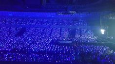 an empty stadium filled with lots of people watching something on the stage and lights in the air