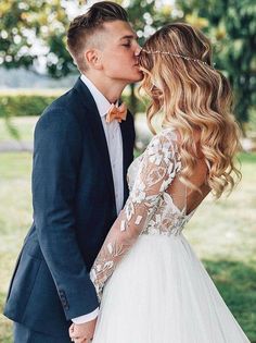 a bride and groom kissing in the park