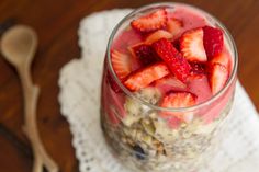 there is a bowl of food with strawberries in it and a spoon next to it