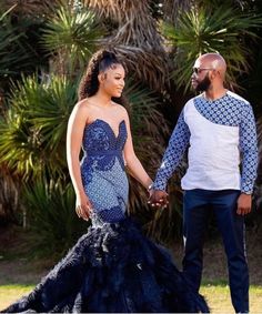 a man and woman holding hands in front of palm trees