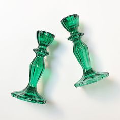 two green glass candlesticks sitting next to each other