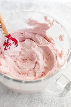 a bowl filled with pink whipped cream and a wooden spoon