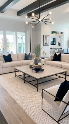 a living room filled with furniture and a chandelier above the coffee table on top of a rug