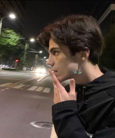 Ragazzo di profilo con i capelli neri black gaie che sta fumando una sigaretta si smoking a cigarette in strada di notte in the steet at night