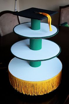 three tiered cake stand with graduation cap on top and tassels at the bottom