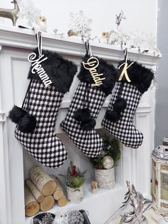 three stockings hanging from the fireplace decorated with black and white checkered fabric, gold foil lettering