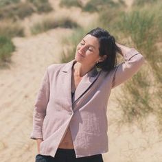 a woman standing in the sand with her hand on her head and looking up at the sky