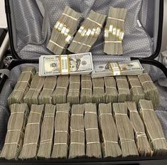 a suitcase filled with lots of money sitting on top of a floor