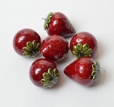 five red strawberries with green leaves on them