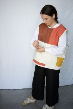 a woman standing in front of a white wall with her hands clasped to her chest