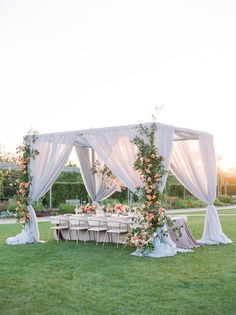 an outdoor wedding setup with white draping and pink flowers on the table set up