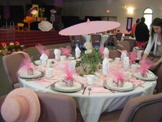 a table set up for a tea party with pink decorations