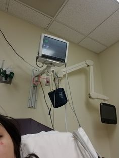 a woman laying in a hospital bed with an iv and monitor attached to the wall