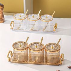 four glass containers with gold handles on a white table