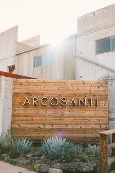 a wooden sign that says arcosani in front of some rocks and succulents