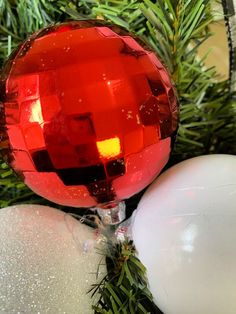 a red ornament sitting on top of a christmas tree next to white balls