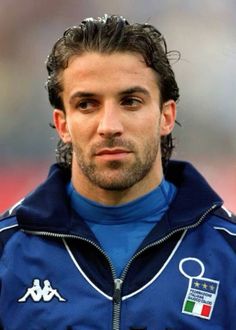 a close up of a soccer player wearing a blue jacket and looking at the camera