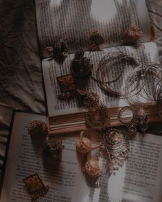 an open book with jewelry laying on top of it next to some candles and bracelets