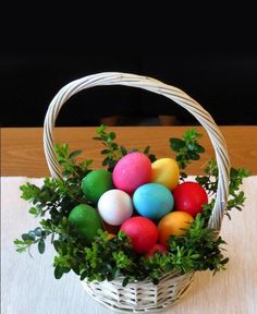 a basket filled with colorful eggs sitting on top of a table