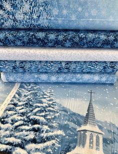 four pieces of blue and white fabric with snow on the ground, church steeple in background