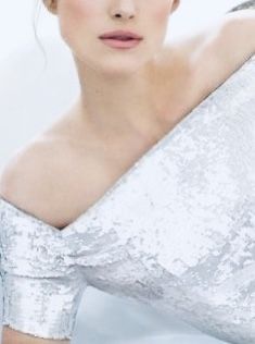 a woman wearing a silver dress posing for a photo with her hair in a bun