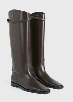 TOTEME's interpretation of classic riding boots have an understated, silver-tone metal monogram decorating the knee-high shaft. They're crafted in Italy from responsibly sourced leather with a pointed square toe, a decorative strap, and a low stacked heel measuring 22mm. Keep them in focus by wearing them with leggings or tucked-in pants. Luxury Calf Leather Knee-high Boots For Business, Classic Knee-high Boots For Business, Luxury Brown Knee-high Boots For Business, Sweater Blazer, In Focus, Leather Riding Boots, Clutch Pouch, Swim Shop, Stacked Heel