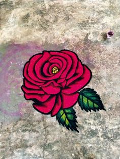 a red rose painted on the ground with green leaves